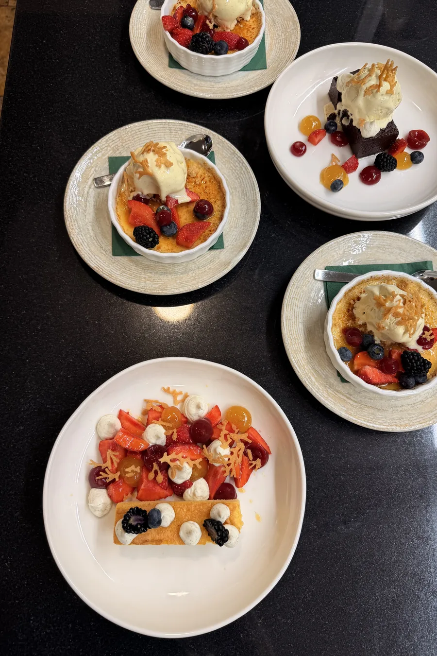 Creme Brulee mit Beeren und Eis, daneben French Toast und Brownie, von oben