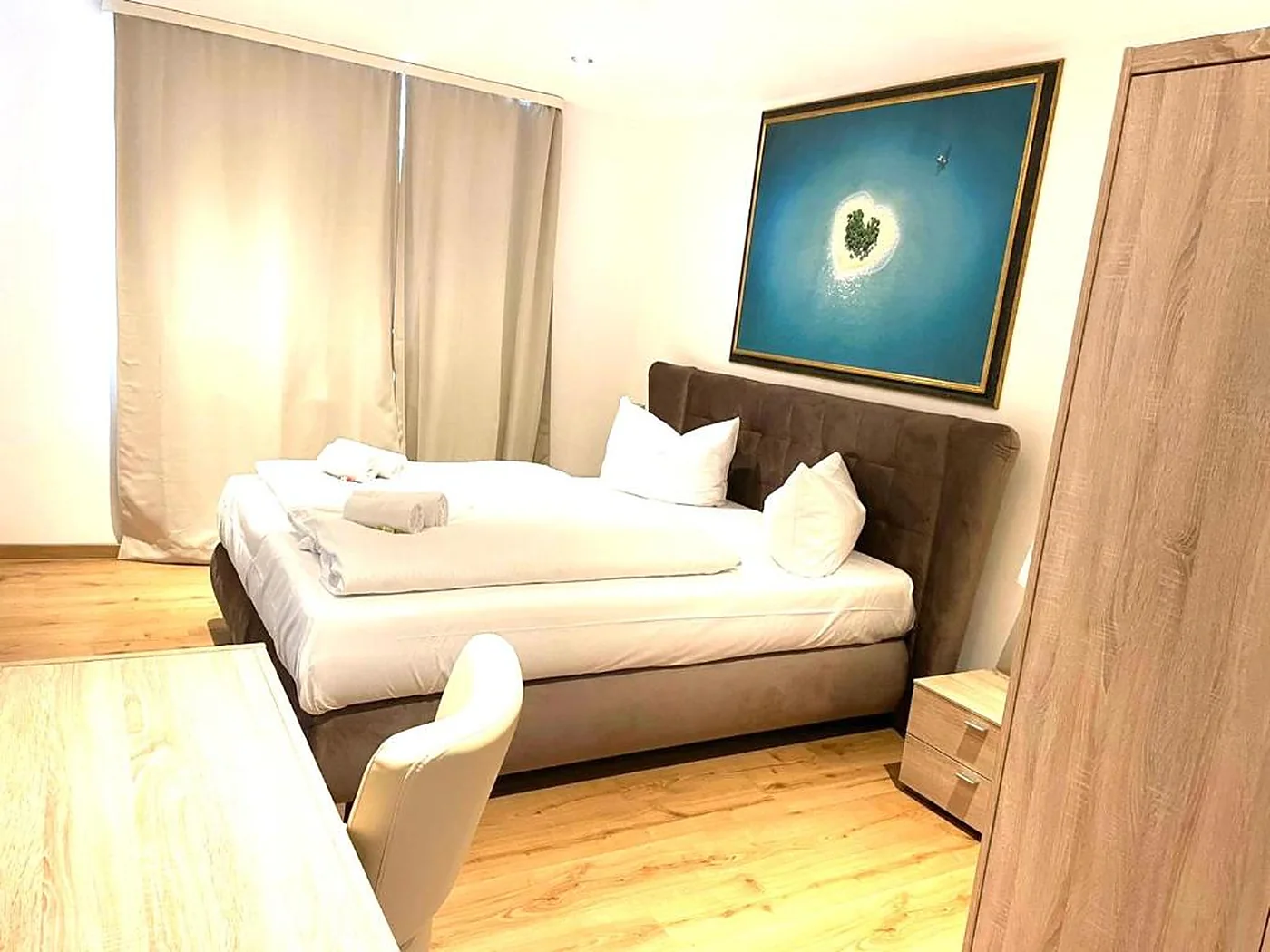 Camera doppia dell’Hotel Anker con testiera imbottita e poltrona
